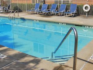 a swimming pool with blue lounge chairs and a swimming pool at Extended Stay America Suites - Oklahoma City - Northwest in Oklahoma City