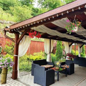 a wooden pergola with chairs and a table with flowers at Hotel Dennis in Mediaş
