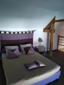 1 dormitorio con 1 cama grande con almohadas moradas en Le Breuil, en Piney