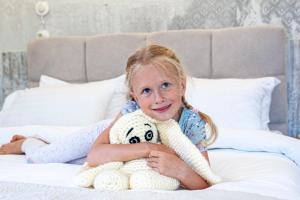 a girl sitting on a bed with a stuffed animal at Biplan Hotel in Daugavpils