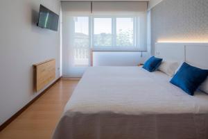 a bedroom with a large bed with blue pillows at Pensión Venus in Nigrán