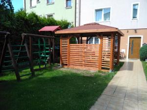 a wooden gazebo in the grass next to a building at Pokoje Goscinne "Anna Maria" in Łeba