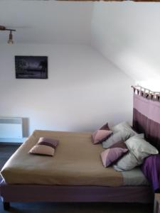 1 cama con almohadas en el dormitorio en Le Breuil, en Piney