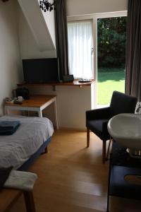 a room with a bed and a table and a window at Hofstede Villetta in Zonnemaire