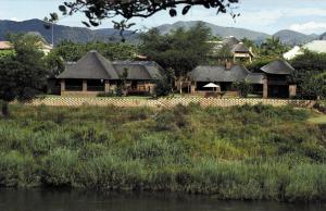 a group of houses with a river in the foreground at Khandizwe Kruger Villa in Malelane