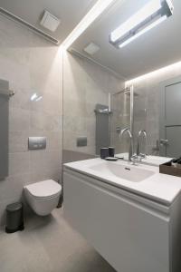 a white bathroom with a sink and a toilet at APARTAMENTAI LEMBERGAS in Vilnius