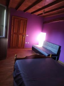 um quarto com paredes roxas e uma cama com um candeeiro em CASA "O Campo" em Sober