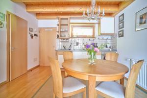 une table à manger avec des chaises et un vase de fleurs dans l'établissement Supperior Appartement, à Rasùn di Sotto