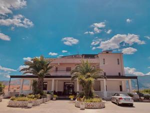 un bâtiment avec des palmiers en face de celui-ci dans l'établissement Hotel Vallisdea, à Sala Consilina