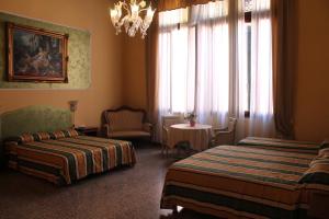 a hotel room with two beds and a chandelier at Palazzo Lion Morosini - Check in presso Locanda Ai Santi Apostoli in Venice