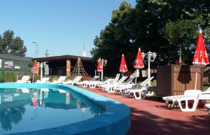 a pool with white chairs and red umbrellas at O&aacute;zis Wellness Panzio in Szigetszentmikl&oacute;s