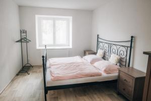 Schlafzimmer mit einem Bett mit rosa Bettwäsche und einem Fenster in der Unterkunft Apartmán v přírodě pro 4 osoby in Jihlava