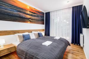a bedroom with a bed with a painting on the wall at Apartament Mariner by Renters in Kołobrzeg