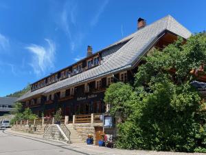 ein großes Holzgebäude mit einem Zinndach in der Unterkunft Hotel Hirschen in Menzenschwand