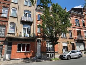 Un coche plateado aparcado delante de un edificio de ladrillos. en Appartement Chez Agnes, en Bruselas