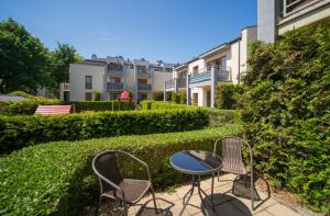 a patio with two chairs and a table and a building at Aurora Apartament Gardenia in Międzywodzie