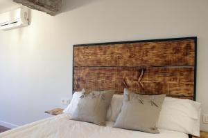 a bed with white pillows and a wooden headboard at Ático Industrial Céntrico, Reformado, Air-Acond, Netflix, WiFi in Salamanca