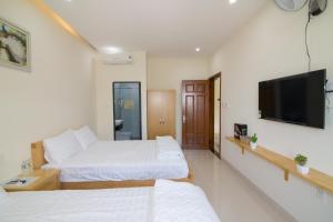 a bedroom with two beds and a flat screen tv at Relax hotel in Quy Nhon