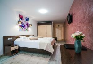 una habitación de hotel con una cama y un jarrón de flores en Hotel Eden, en Câmpulung Moldovenesc