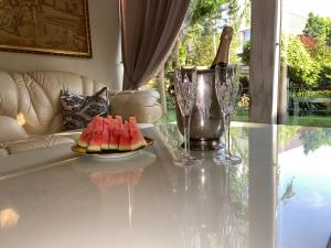 a table with a plate of watermelon and wine glasses at Cosy and peaceful apartment in Kaunas