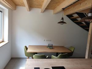 a dining room with a wooden table and green chairs at Beim Hooch. Lisbeth in Brücktal