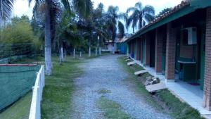 un chemin de terre à côté d'un bâtiment planté de palmiers dans l'établissement Chacara Descanso do Rei, à Vinhedo