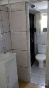 La salle de bains blanche est pourvue de toilettes et d'un lavabo. dans l'établissement Chacara Descanso do Rei, à Vinhedo