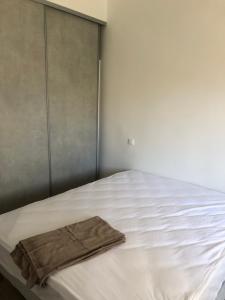 a white bed with a brown towel on it at Appartement Place du Marché Bastia in Bastia