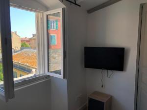 a flat screen tv on a wall next to a window at Appartement Place du Marché Bastia in Bastia