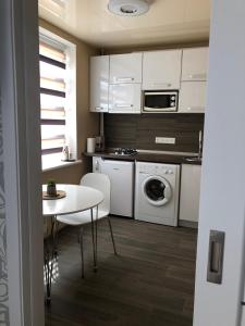 a kitchen with white cabinets and a table and a washer at Сдам посуточно однакомнатную квартиру in Kharkiv