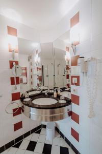 ein Badezimmer mit einem Waschbecken und einem großen Spiegel in der Unterkunft Hotel Ars Vivendi München in München