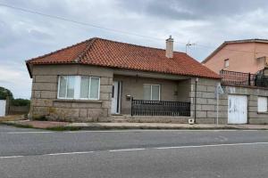 ein Backsteinhaus mit rotem Dach auf einer Straße in der Unterkunft CASA QUINTEIROS in O Grove