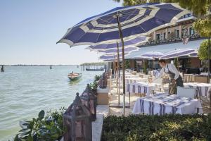 a restaurant with tables and umbrellas next to the water at Cipriani, A Belmond Hotel, Venice in Venice