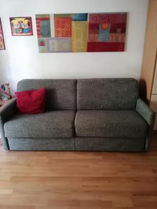 ein graues Sofa mit einem roten Kissen unter einem Gemälde in der Unterkunft Appartamento MaVi in Vals