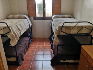 two beds in a room with a tiled floor at Amplio apartamento de montaña con terraza y WiFi in Canfranc