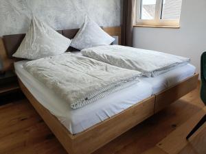 a bed with white sheets and pillows on it at Ferienhaus am Funkenbühl in Salem