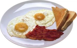 a plate of eggs bacon and toast on a white plate at Family hotel Iskar in Govedartsi