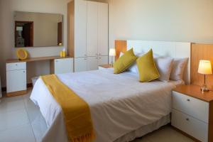 um quarto com uma grande cama branca com almofadas amarelas em Triunfo Guest House em Maputo