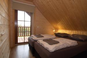 two beds in a wooden room with a window at Houten Villa Dirk in Den Ham