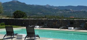 two chairs and a swimming pool with mountains in the background at Agriturismo Sa Murta in Sennariolo