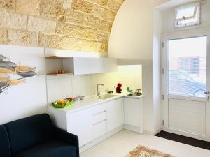 een keuken met witte kasten en een zwarte stoel bij B&B Suite Amare Polignano in Polignano a Mare