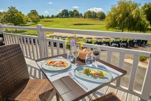 una mesa con dos platos de comida y copas de vino en Saint Malo Golf Resort, en Le Tronchet
