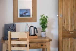 einen Holzschreibtisch mit einem Wasserkocher und einer Topfpflanze in der Unterkunft The Haughmond in Shrewsbury