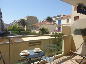 einen Tisch auf einem Balkon mit zwei Tassen und einem Stuhl in der Unterkunft STUDIO LES ALGUES in Cannes