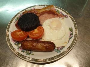 a plate of food with an egg sausage and tomatoes at Lancaster Hotel in Oban