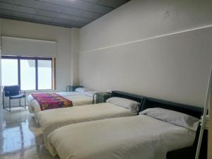 Habitación con 4 camas y una silla. en Acolá Rooms, en Pontevedra