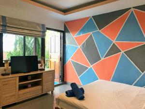 Lanta Halabala Resort في كو لانتا: غرفة نوم مع جدار ملون مع سرير وتلفزيون