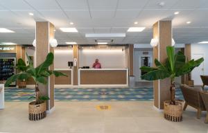 a lobby with palm trees and a person standing at a counter at Medplaya Hotel Regente in Benidorm