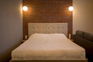 a white bed in a room with a brick wall at Modern apartmetns in town center in Poltava