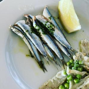 un plato de comida con pescado y guisantes y un limón en Hotel Mayola, en San Bartolomeo al Mare